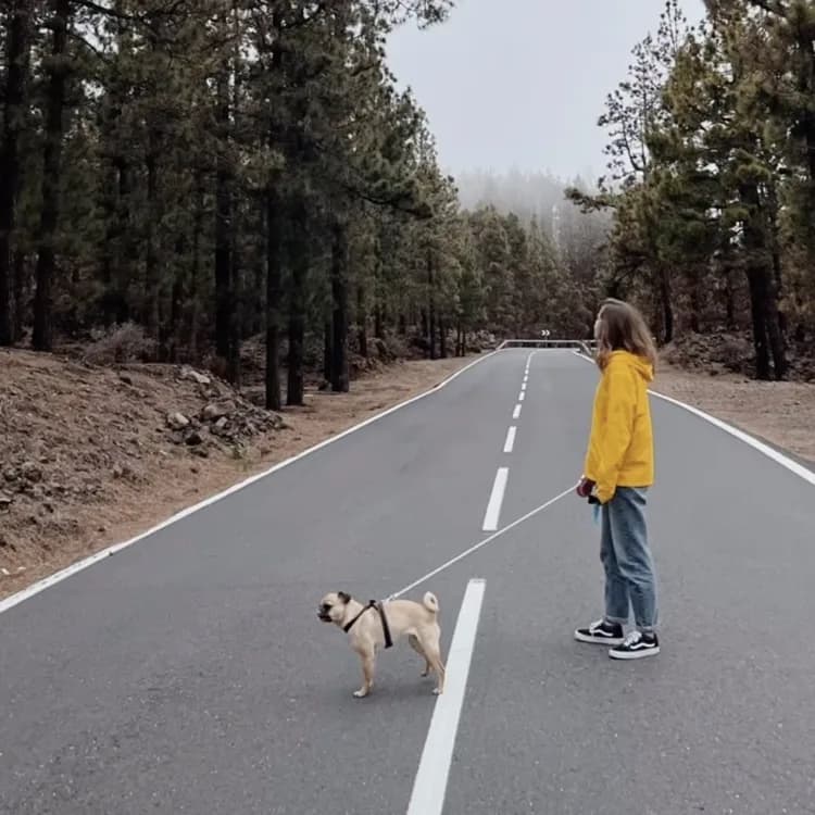 Lorena paseando a su perro por una carretera de montaña